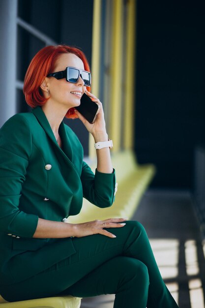 Biznesowa kobieta w zielonym garniturze za pomocą telefonu