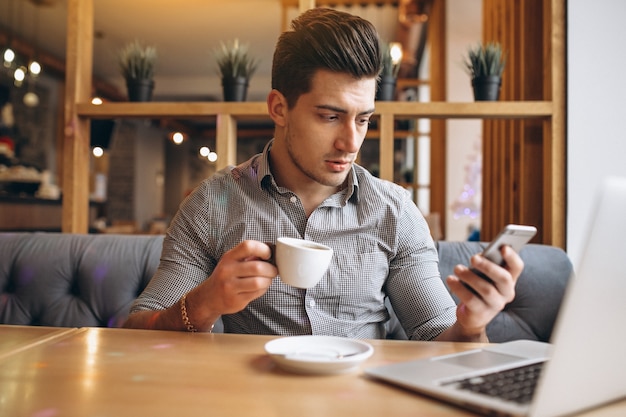 Biznesowy mężczyzna opowiada na telefonie i pije kawę w kawiarni