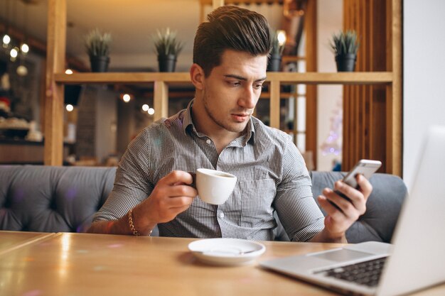 Biznesowy mężczyzna opowiada na telefonie i pije kawę w kawiarni