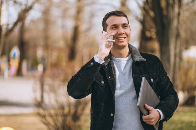 Biznesowy mężczyzna opowiada na telefonie outside w parku