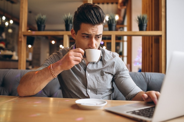 Biznesowy mężczyzna pije kawę w kawiarni z laptopem