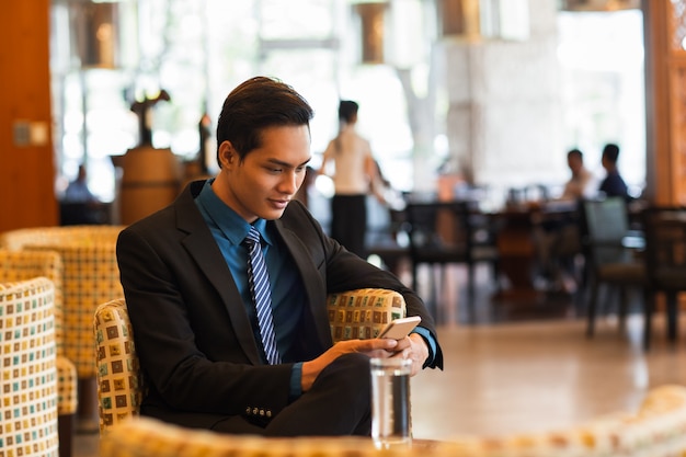 Biznesowy treść Man Texting na telefon w Cafe