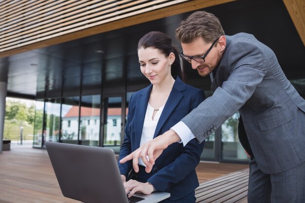 Bizneswoman i kolega za pomocą laptopa