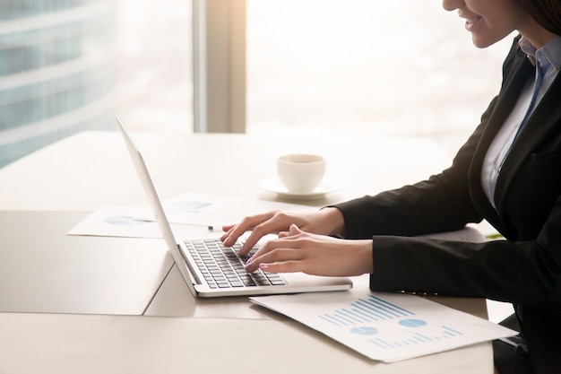Bizneswoman pracuje z diagramami przy biurowym używa laptopem, zamyka up