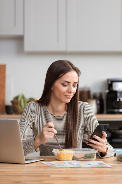 Bizneswoman próbuje jeść i pracować z jej telefonu