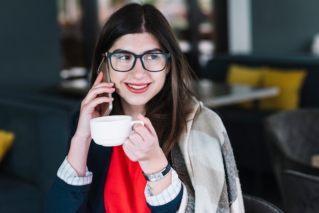 Bezpłatne zdjęcie bizneswoman robi rozmowie telefonicza w sklep z kawą