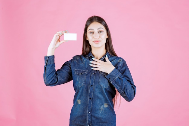 Bezpłatne zdjęcie bizneswoman trzyma wizytówkę i wskazuje na siebie