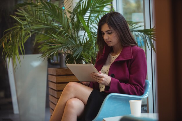 Bizneswoman używa cyfrowego pastylkę w café