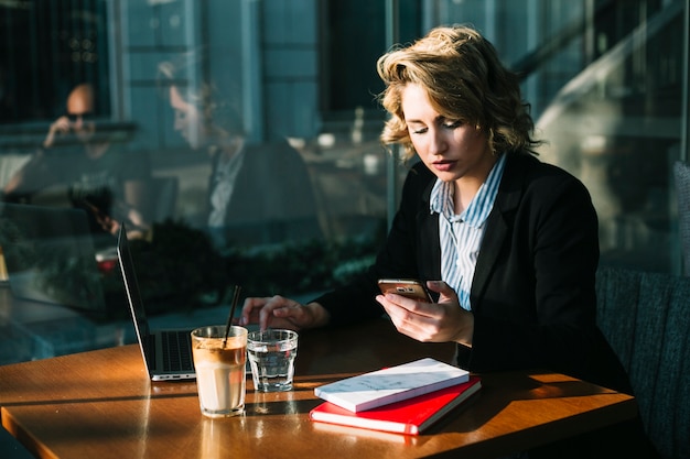 Bizneswoman używa laptop i telefon komórkowego w restauraci