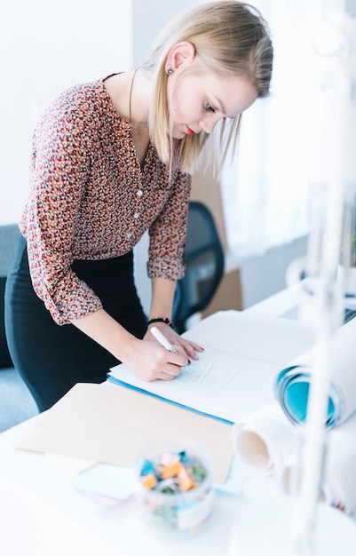 Bezpłatne zdjęcie bizneswomanu writing na papierze nad biurowym biurkiem