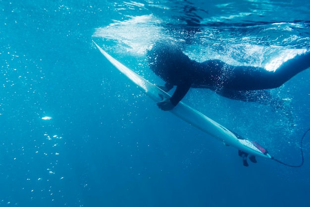 Bliska człowiek z deską surfingową pod wodą