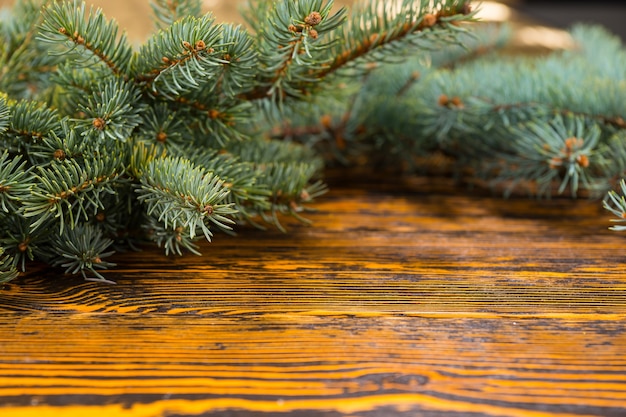 Bliska martwa natura świątecznych wiecznie zielonych gałęzi kadrowania miejsca kopiowania na rustykalnym drewnianym stole z słojami drewna i selektywnym ustawianiem ostrości