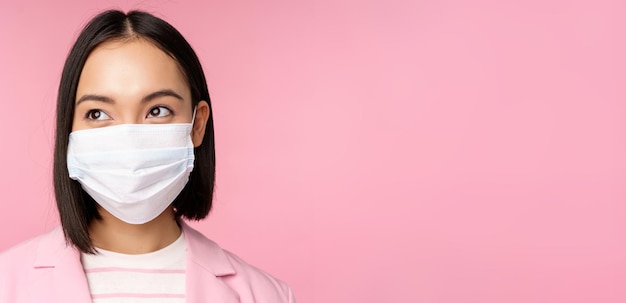 Bliska portret japońskiej kobiety korporacyjnej w medycznej masce na twarz z covid, patrząc w lewo na logo s