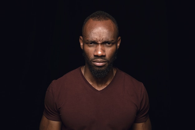 Bliska portret młodego mężczyzny afrykańskiego na czarnym tle