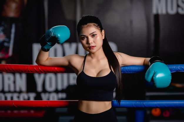 Bliska portret młodej ładnej kobiety w rękawicy bokserskiej stojącej na płótnie po treningu ze zmęczonym, trening w siłowni fitness
