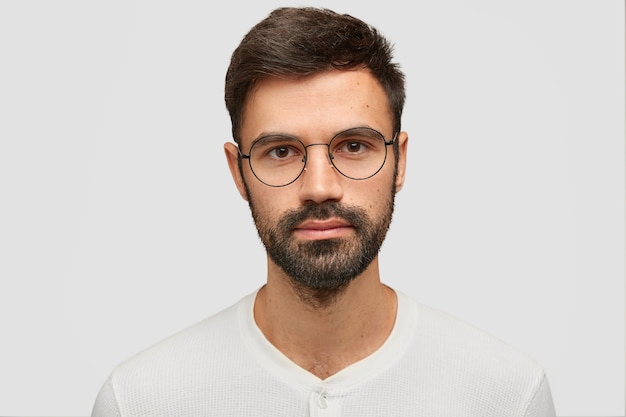 Bliska portret przystojny nieogolony mężczyzna z gęstą brodą i wąsami, ma ciemne włosy, wygląda poważnie