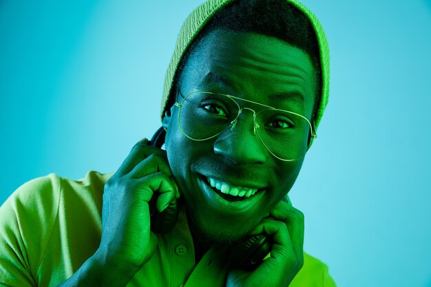 Bliska portret szczęśliwego młodego człowieka Afroamerykanów, uśmiechając się na tle czarnego studia neonowego
