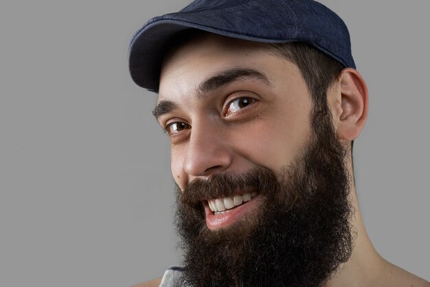 Bliska portret szczęśliwy i uśmiechnięty brodaty mężczyzna w studio na szarym tle.