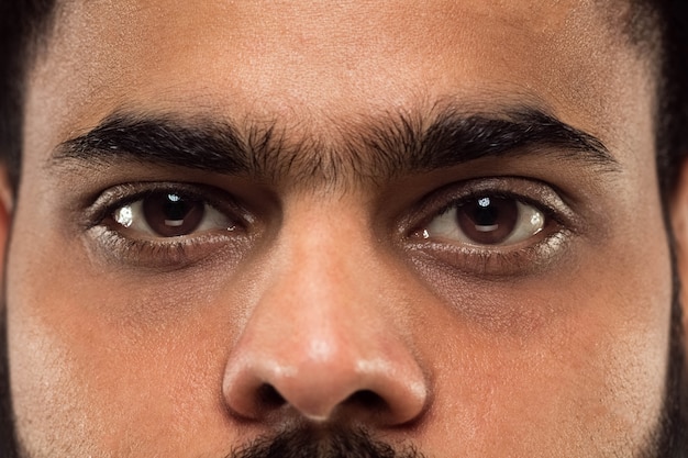 Bliska portret twarzy młodego człowieka hinduskiego z brązowymi oczami patrząc prosto w kamerę