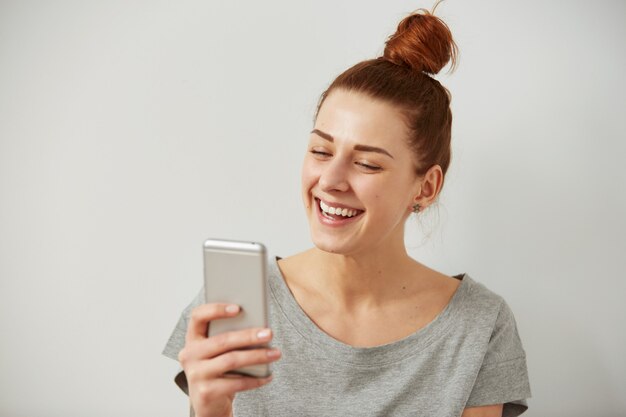 Bliska portret uśmiechnięta lub śmiejąca się młoda kobieta freelancer patrząc na telefon