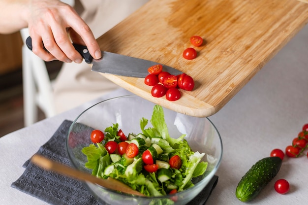 Bliska ręcznie umieszczanie pomidorów w sałatce
