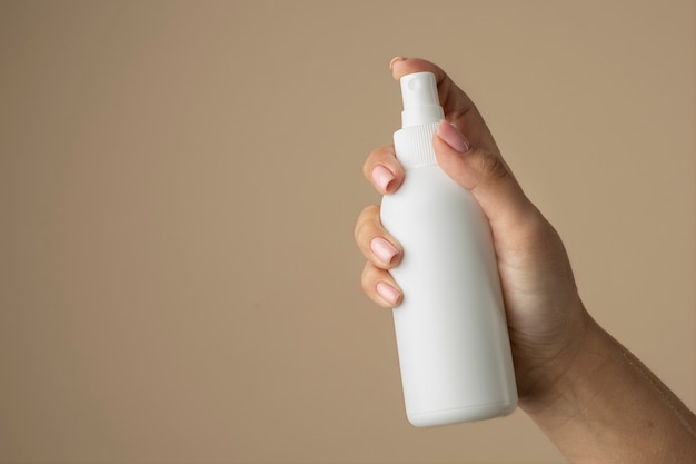 Bliska ręka trzymająca butelkę z rozpylaczem