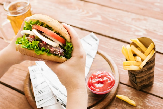 Bezpłatne zdjęcie bliska szczegół kąt ręce trzymając burger z burger z frytkami