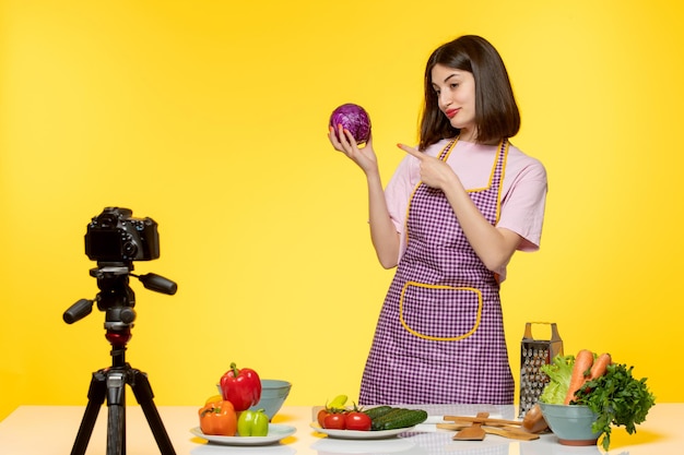 Blogerka Kulinarna Urocza Urocza Dziewczyna W Różowym Fartuchu Nagrywa Wideo Dla Mediów Społecznościowych Pokazujące Cebulę