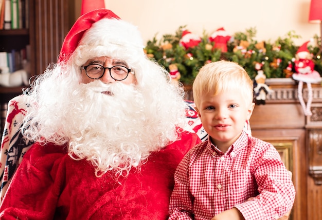 Bezpłatne zdjęcie blond chłopiec siedzi w santa nóg