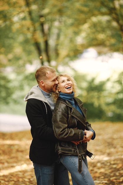 Blond kędzierzawa kobieta i mężczyzna stojący w jesiennym lesie i przytulający się