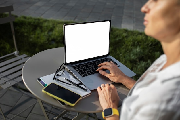 Blond kobieta biznesu pracuje na swoim laptopie na zewnątrz