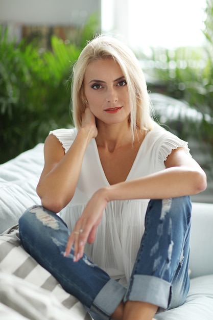 Bezpłatne zdjęcie blond kobieta relaksuje na kanapie w domu