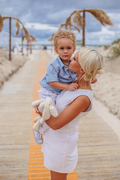 Blond kobieta trzyma dziecko nad drogą na plażę.