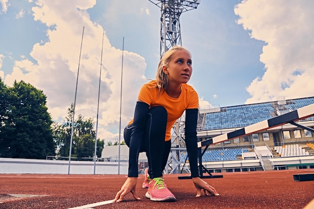 Bezpłatne zdjęcie blond sportowy biegacz do pozycji szybkiego startu.