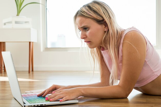 Blonde influencer używający laptopa na podłodze