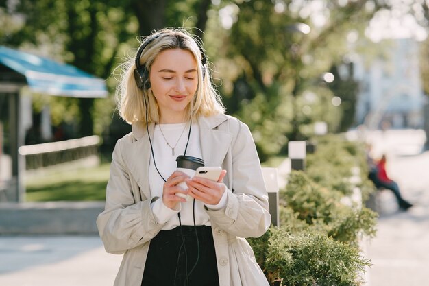 Blondynka chodzi w lecie miasta z filiżanką kawy