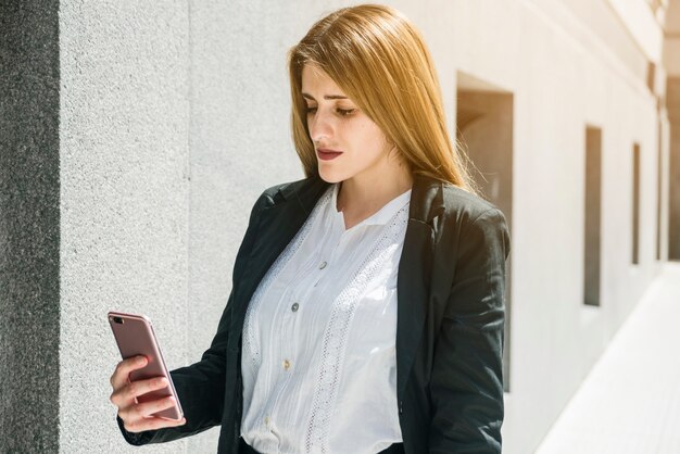 Blondynka młody bizneswoman patrzeje smartphone