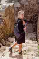 Bezpłatne zdjęcie blondynka patrzy w lewo w czarnej sukience na kamiennym tle