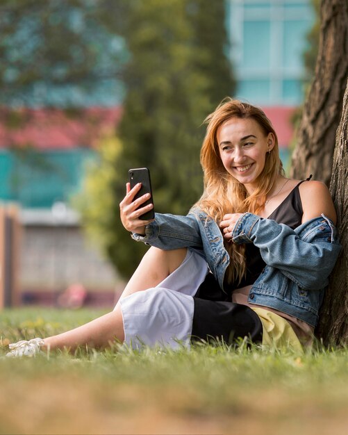 Blondynka robi selfie obok drzewa