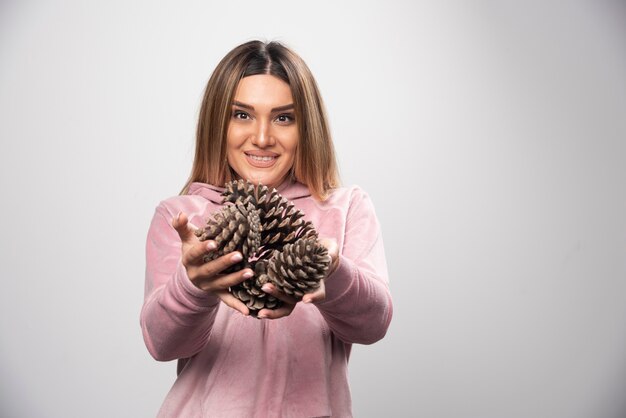 Blondynka w różowej bluzie z radością w dębowych szyszkach.