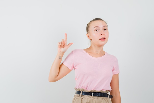 Blondynka w t-shirt, spodnie skierowaną w górę i patrząc pewnie, widok z przodu.