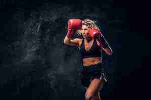 Bezpłatne zdjęcie blondynka z doświadczeniem w bokserce demonstruje swój taktyczny atak w specjalnych rękawiczkach.
