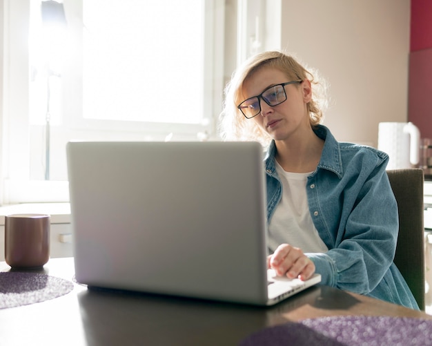 Blondynki kobieta pracuje na laptopie w kuchni