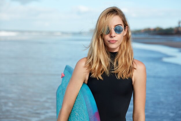 Blondynki kobieta z deską surfingową na plaży