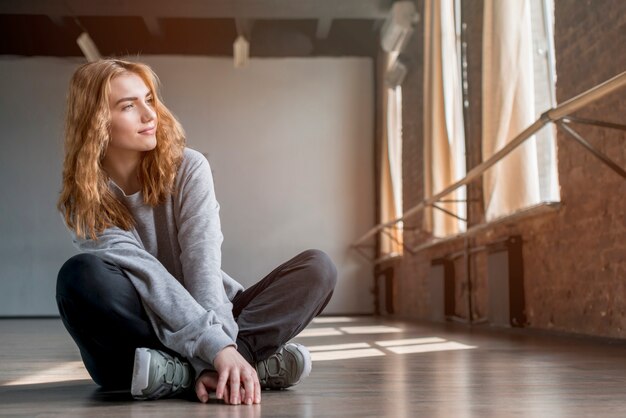 Blondynki młoda kobieta siedzi na drewnianej podłodze w studiu tańca