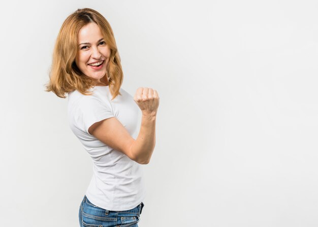 Blondynki młoda kobieta zaciska jej pięści pozycję przeciw białemu tłu