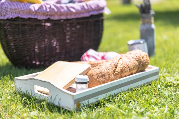 Bezpłatne zdjęcie bochen chleba; deska do krojenia i solniczka w zasobniku na zielonej trawie