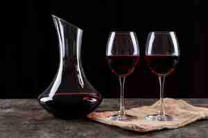 Bezpłatne zdjęcie bocznego widoku czerwone wino w szkłach i bieliźnianym płótnie na ciemny horyzontalnym