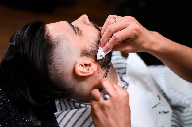 Bocznego widoku fryzjera męskiego klienta brody tnący zakończenie