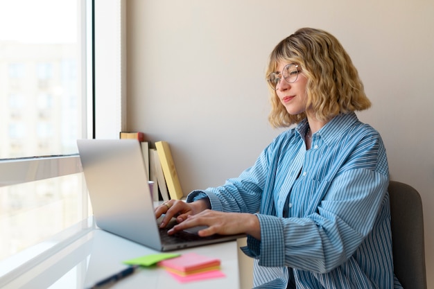 Bezpłatne zdjęcie bocznego widoku kobieta pracuje na laptopie